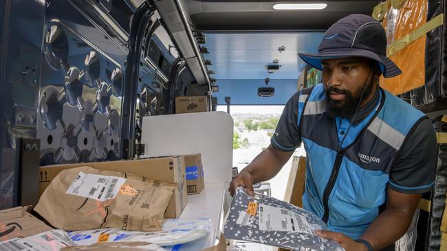 Amazon employee using the new VAPR technology, which projects a green circle on the correct parcel for delivery and red Xs on all the others.