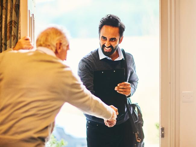 Young male community healthcare worker being welcomed by a senior man at his home; Aged care home care visit, senior generic