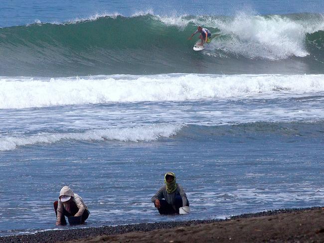 Locals look for ornamental shells on the surf beach at Keramas, Bali. Picture: John Borthwick