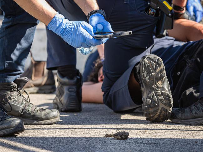 Police take photographs of rocks allegedly found in a man’s pockets. Picture: Jason Edwards