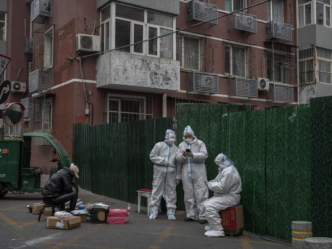 BEIJING, CHINA - NOVEMBER 24: Epidemic control workers wear protective suits as they guard in front of a  barrier fence in an area under lockdown to prevent the spread of COVID-19 on November 24, 2022 in Beijing, China. China recorded its highest number of COVID-19 cases since the pandemic began Wednesday, as authorities stuck to their strict zero tolerance approach: containing the virus with lockdowns, mandatory testing, mask mandates, and quarantines as it struggles to contain outbreaks. In an effort to try to bring rising cases under control, the government last week closed most stores and restaurants for inside dining, switched schools to online studies, and asked people to work from home. (Photo by Kevin Frayer/Getty Images)