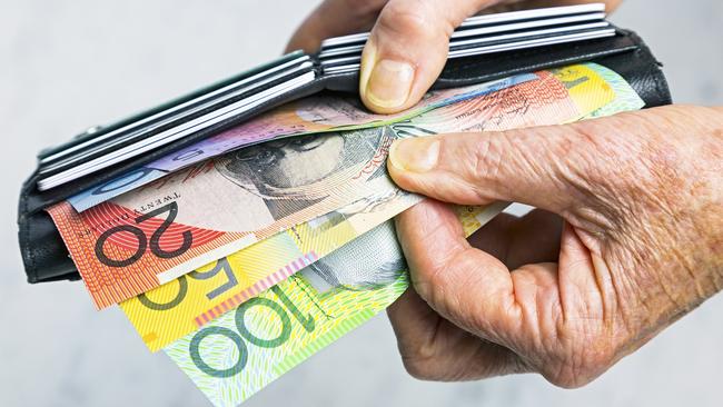 Close-up, senior female hands taking Australian banknotes (cash, currency) from purse containing many credit cards.  Horizontal, studio, copy space. Money generic