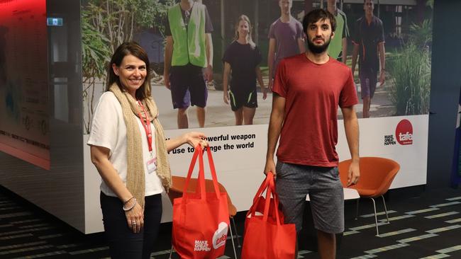 Queensland TAFE Gold Coast student Lucas Bielefeld from Chile receiving a care package from Emma Cross, a student retention and mentoring officer at TAFE’s Ashmore campus. Photo: Supplied.