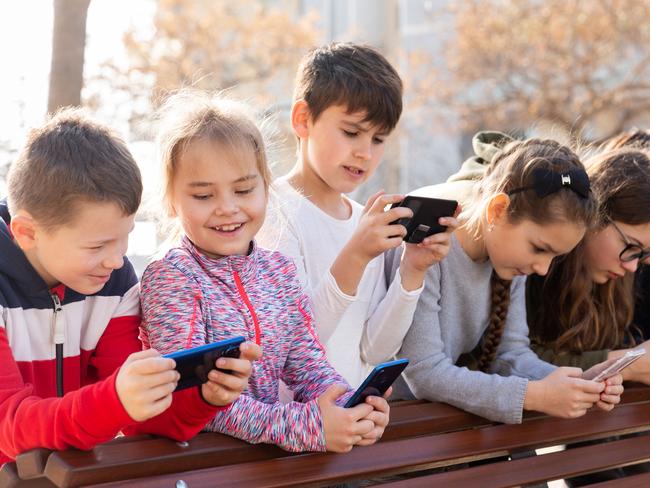 Group of children playing with smartphones outdoors at sunny spring day. Children with smartphones generic