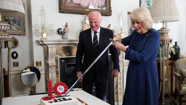 President of The Poppy Factory Surgeon Rear Admiral Lionel Jarvis helps Britain's Queen Camilla to slice a cake with a sword. Picture: Getty Images