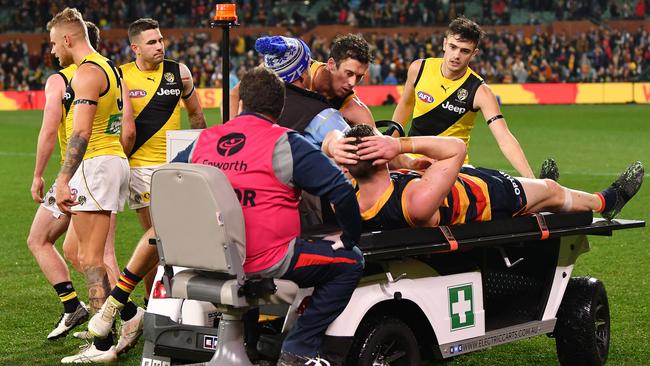 Richmond players console injured Adelaide forward Josh Jenkins.