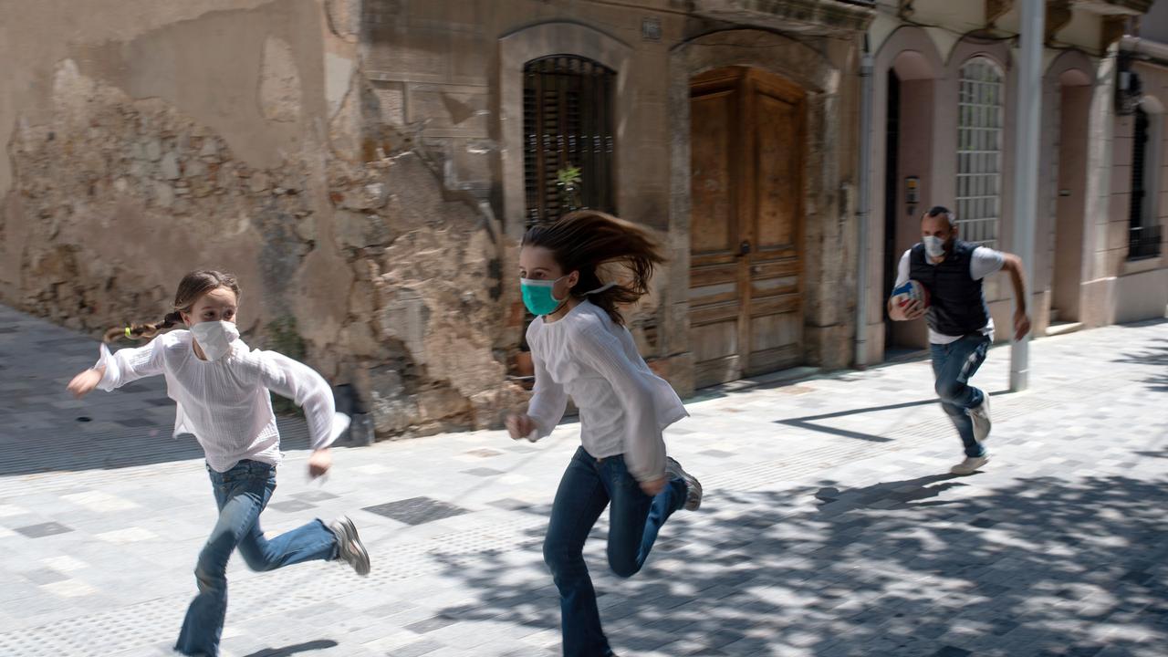 Joan, 45, chases his daughters Ines, 11, and Mar, 9, as they play in the streets of Barcelona. Spain's children are now allowed outside today to run, play or go for a walk. Picture: Josep Lago/AFP