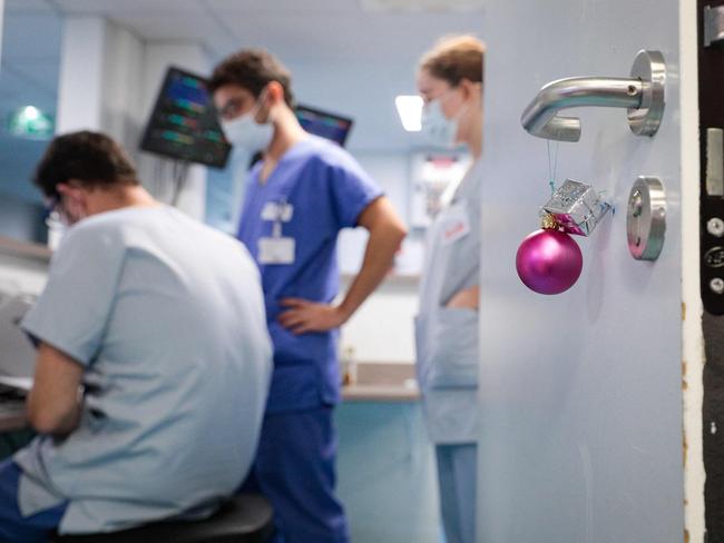 Medical staff members work next to a Christmas decoration at the intensive care unit of the Antoine Beclere hospital in Clamart, outside Paris, on December 23, 2021. - European nations reimposed tough rules and China locked down millions on December 23, 2021, as countries scrambled to contain surging coronavirus infections driven by the Omicron variant. (Photo by GEOFFROY VAN DER HASSELT / AFP)