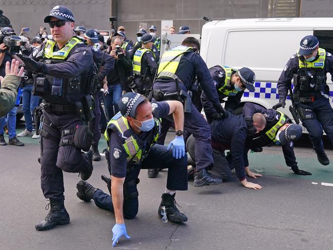 Police officers detain a man as protesters gather outside Parliament House in Melbourne, Sunday, May 10, 2020. Anti-vaxxers and Victorians fed up with the coronavirus lockdown have broken social distancing rules to protest in Melbourne's CBD on Mother's Day. (AAP Image/Scott Barbour) NO ARCHIVING