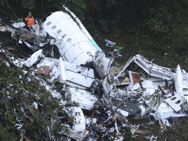 Rescue workers stand at the wreckage site of a chartered aeroplane that crashed outside Medellin, Colombia. Picture: AP