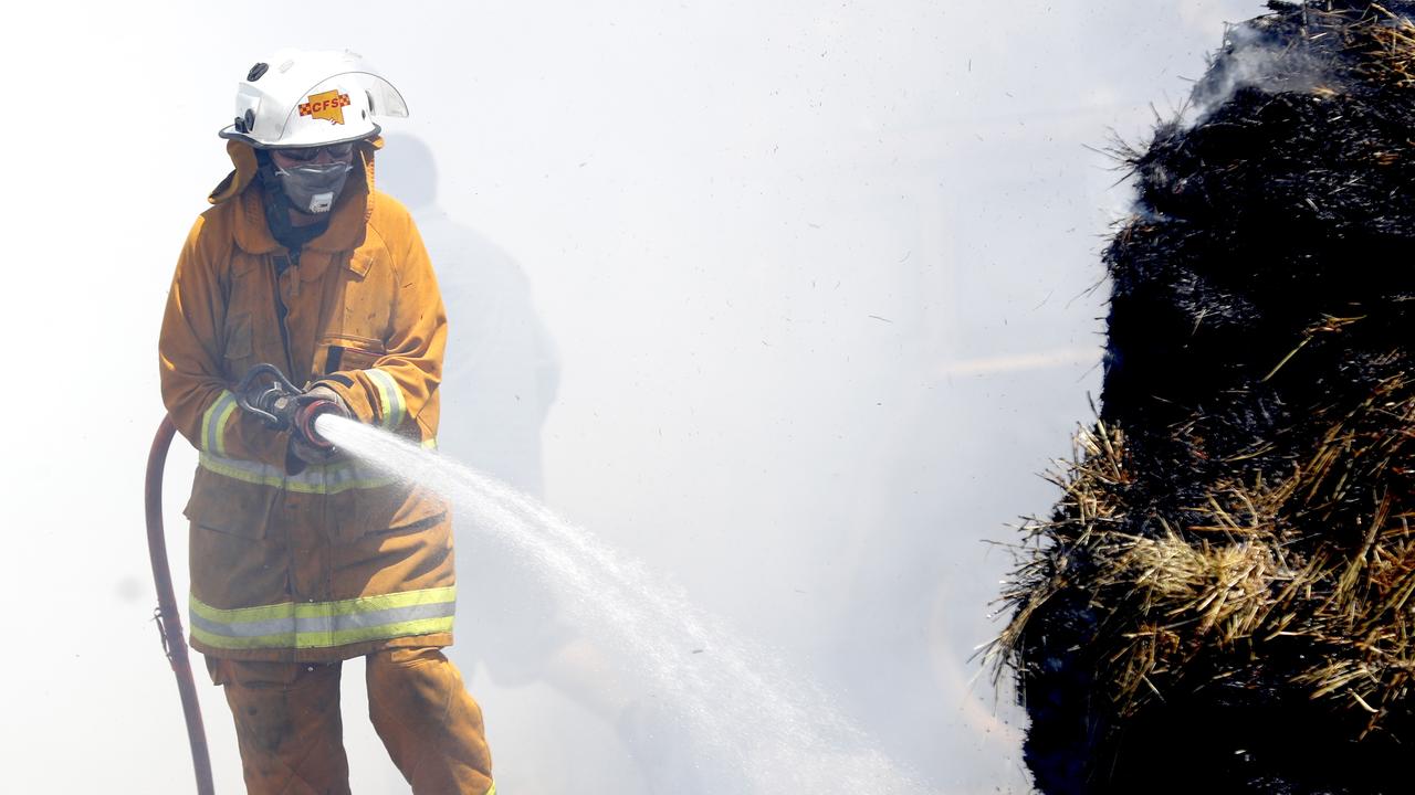 CFS members put out a fire which reached Hay bails on a property at Mount Torrens in the Adelaide Hills. Picture: Kelly Barnes