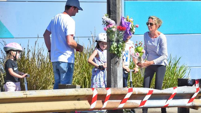 A family places flowers at the site of the crash. Picture: Tony Gough