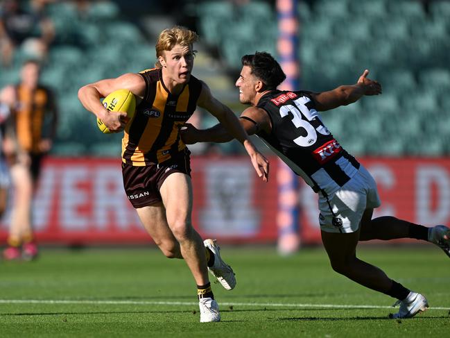 Cam Mackenzie of the Hawks breaks the tackle of Nick Daicos of the Magpies. Picture: Steve Bell