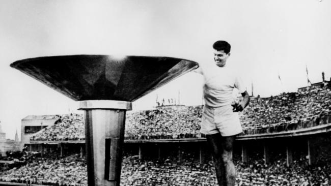 Aust athlete Ron Clarke lighting flame from Olympic torch at MCG in 1956.