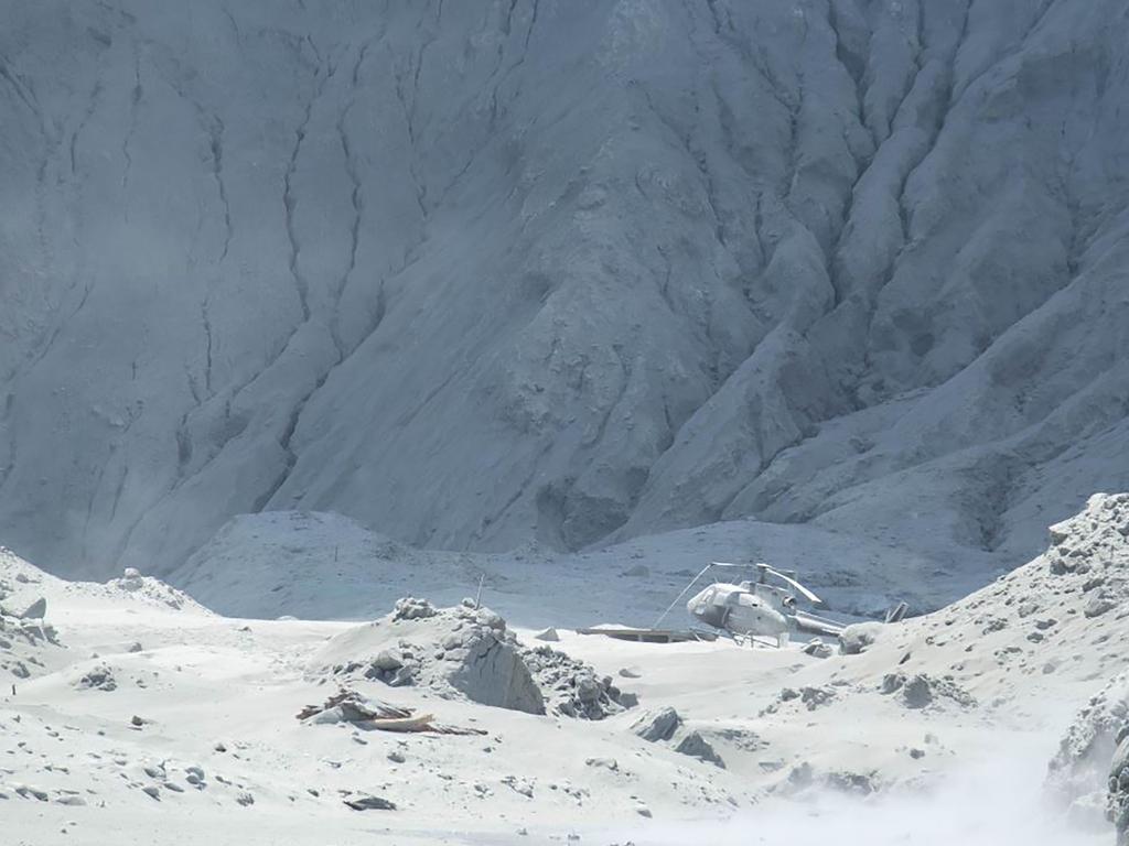 Michael Schade’s picture shows the wreckage of a helicopter amid ash minutes after the volcano on New Zealand's White Island. Picture: Michael Schade / AFP.