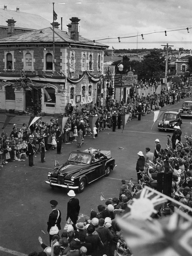 Queen Elizabeth II and Prince Philip drive past a waving crowd in 1954.