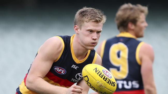 Debutant Fischer McAsey gets a handball away for Adelaide.