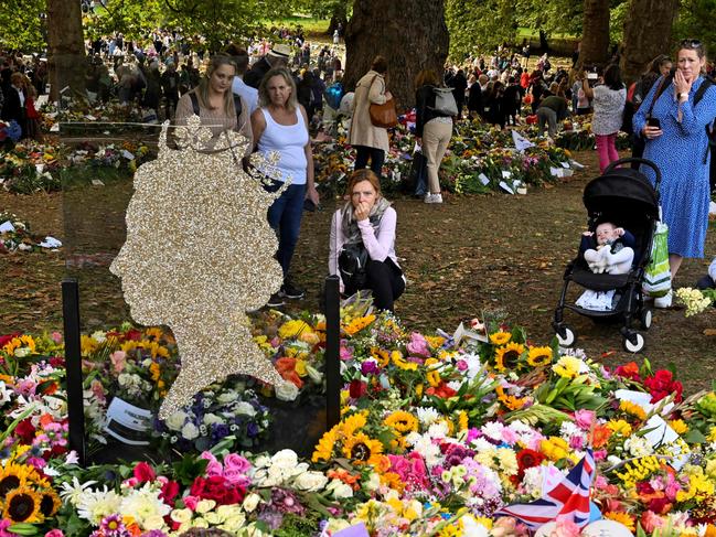 Members of the public look at flowers and tributes left in Green Park in London. Picture: AFP.