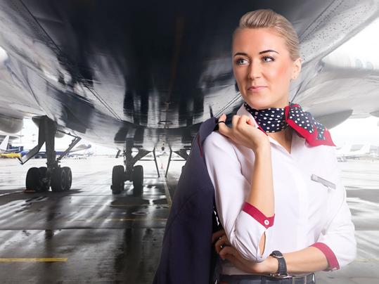 Attractive flight attendant near airplane in airport.