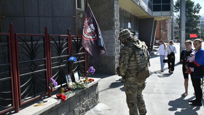 A member of Wagner pays tribute to Prigozhin at the makeshift memorial in front of the PMC Wagner office in Novosibirsk.