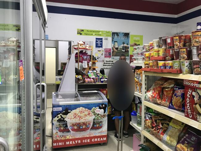 A school kid is served by Mr Murray at the convenience store.