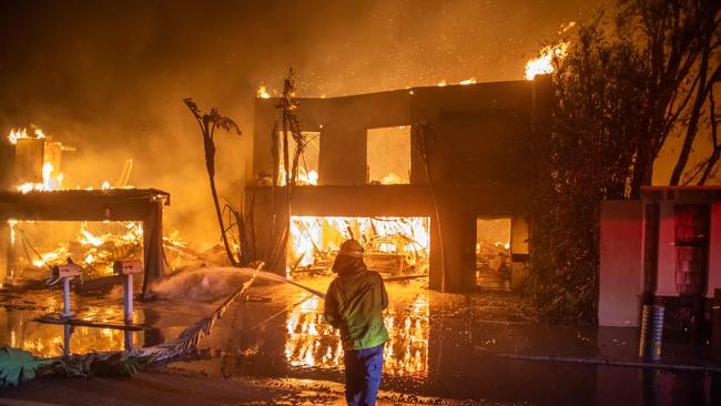 A firefighter battles the Palisades Fire while it burns homes at Pacific Coast Highway amid a powerful windstorm. Picture: Getty