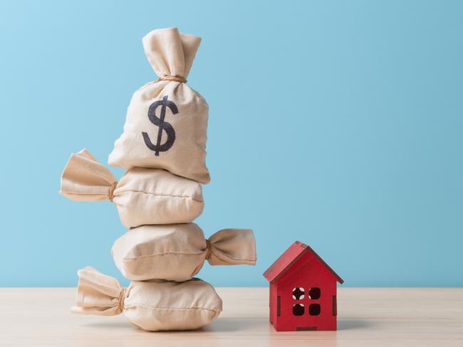 Money bags with Dollar sign and small red house model over blue background with copy space. Concept of house buying and mortgage; housing wealth generic