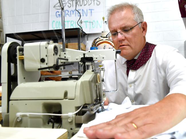 BRISBANE, AUSTRALIA - NewsWire Photos May 17, 2021:  Prime Minister The Hon. Scott Morrison MP  gets behind a sewing machine with the help from Lilian Armitage (Product Developer) at Struddyâs in LoganholmePicture: NCA NewsWire / John Gass