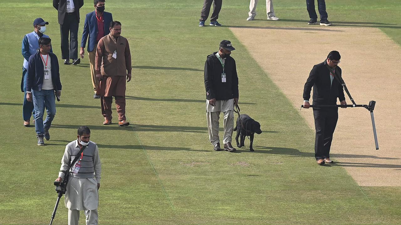 Security personnel use metal detectors to search the ground before the Test