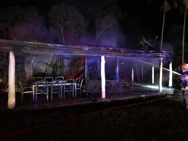 Firefighters dampen down what remains of a house after a fire tore through it at Hampden, north of Mackay, on Wednesday night.