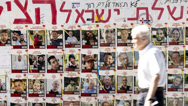 A man walks by a wall covered with photos of hostages held by Hamas in the Gaza Strip (Photo by Amir Levy/Getty Images)