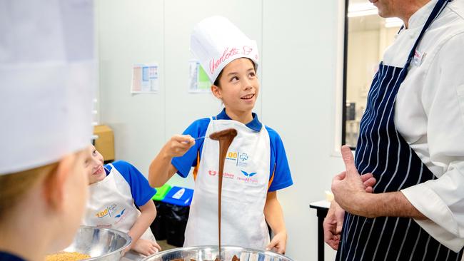 Charlotte Davis with local Girl Guides preparing food at FareShare, Morningside. PICTURES: AAP/Richard Walker