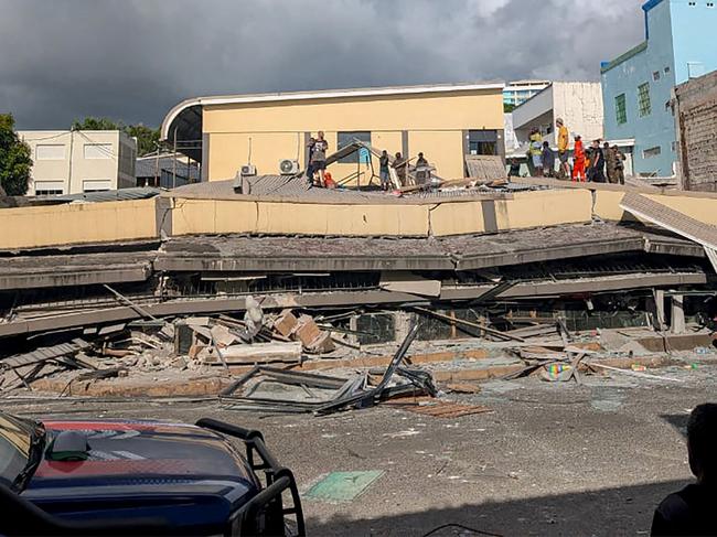 Rescue workers are seen at the site of a collapsed building after a powerful earthquake struck Port Vila, the capital city of Vanuatu, on December 17, 2024. A powerful earthquake hit the Pacific island of Vanuatu on December 17, smashing buildings in the capital Port Vila including one housing the US and other embassies, with a witness telling AFP of bodies seen in the city. (Photo by AFP)