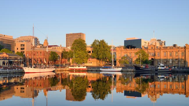 The Hobart fishing marina and city skyline with reflections of the surrounding object in the water.