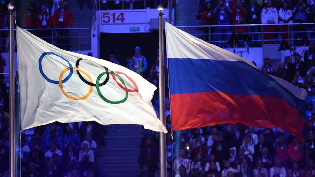 (FILES) In this file photo taken on February 23, 2014 The Olympic flag (L) and the Russian flag flutter during the Closing Ceremony of the Sochi Winter Olympics at the Fisht Olympic Stadium. - The World Anti-Doping Agency (WADA) decided on December 9, 2019, to exclude Russia from the Olympic Games for four years, including Tokyo-2020 and Beijing-2022, to sanction the falsification of test data submitted to the agency, a WADA spokesman said after the Executive Committee meeting in Lausanne. (Photo by Damien MEYER / AFP)