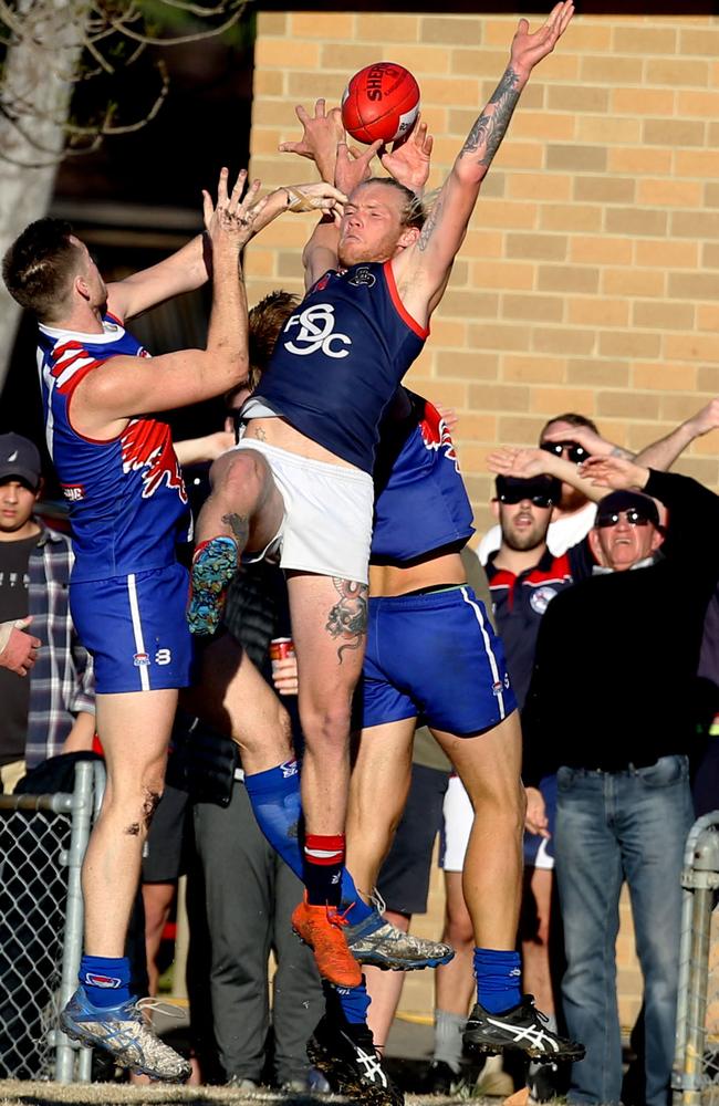 Springvale Districts defender Ben Stacey flies for a mark in front of spectators including Districts legend David Hall (right). Picture: Stuart Milligan