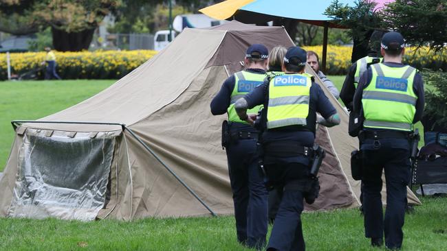 Police and council workers warn protesters to pull down their tents in Carlton Gardens on Tuesday morning. Picture: David Crosling