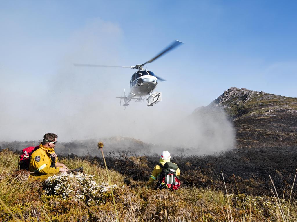 Parks and TFS firefighters watch for a waterbombing aircraft to strafe the fire edge before smothering the burnt remains with beaters/ hand tools. Picture: WARREN FREY / TASMANIA FIRE SERVICE