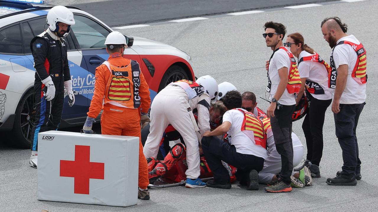 Francesco Bagnaia receives medical assistance after the crash. (Photo by LLUIS GENE / AFP)