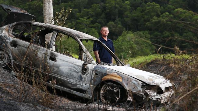 Bentley Park resident Brett Davenport looks over a burnt-out car, the fire brigade had to attend to the blaze. Picture: BRENDAN RADKE