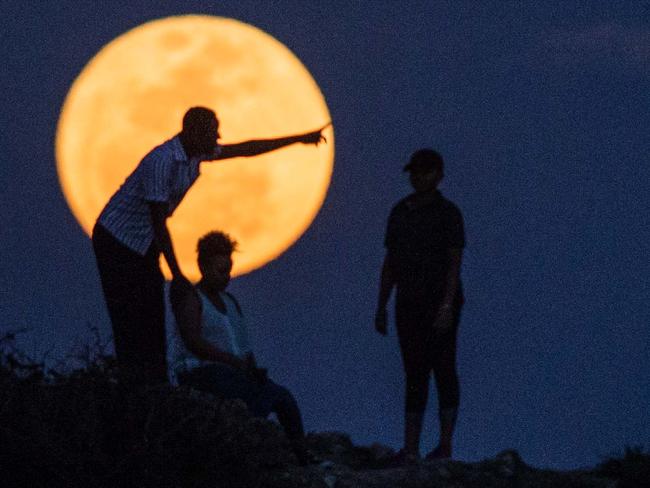 People watch the supermoon rising in Dar es Salaam on November 14, 2016. The moon will be the closest to Earth since 1948 at a distance of 356,509 kilometres (221,524 miles), creating what NASA described as "an extra-supermoon". / AFP PHOTO / DANIEL HAYDUK