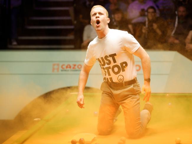 SHEFFIELD, ENGLAND - APRIL 17: A Just Stop Oil protester jumps on the table and throws orange powder during the first round match between Robert Milkins and Joe Perry on day 3 of the 2023 Cazoo World Championship at Crucible Theatre on April 17, 2023 in Sheffield, England. (Photo by VCG/VCG via Getty Images)