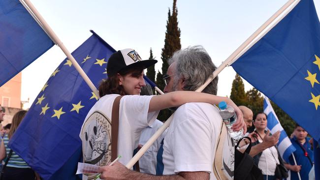 Protesters hug while holding EU flags during a pro-European Union demonstration in front of the Greek parliament in Athens by the 'we stay in Europe' movement on July 9, 2015. Greece was to submit a detailed bailout request to its eurozone partners on July 9 in a last-ditch effort to save its collapsing economy and its place in the euro, in an unprecedented test of EU cohesion. With the crisis reaching a climax that could have unpredictable consequences, the EU president urged creditors to compromise on granting debt relief to Greece. AFP PHOTO/ LOUISA GOULIAMAKI - FRANCE OUT -