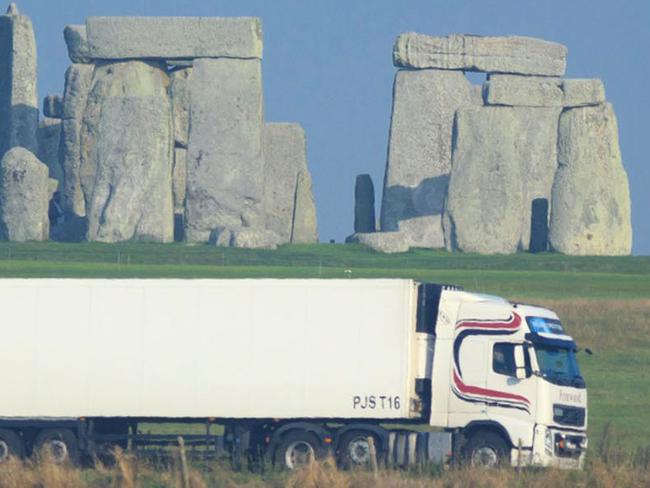 This is an undated handout photo issued by the National Trust, via the Press Associated of a truck passing Stonehenge on the A303 road in Wiltshire England. Visitors to Stonehenge will no longer have to shut out the sound of thundering traffic as they admire ancient monument. The 1.8-mile (2.9 kilometer) tunnel, part of a 2 billion pound ($3.2 billion) upgrade to the road, will eliminate motorists’ view of the stone circle. But Helen Ghosh, director of heritage group the National Trust, said visitors to the site "will once again be able to hear the sounds of skylarks singing rather than the constant noise of traffic." (AP Photo/John Miller/National Trust/PA) UNITED KINGDOM OUT NO SALES NO ARCHIVE