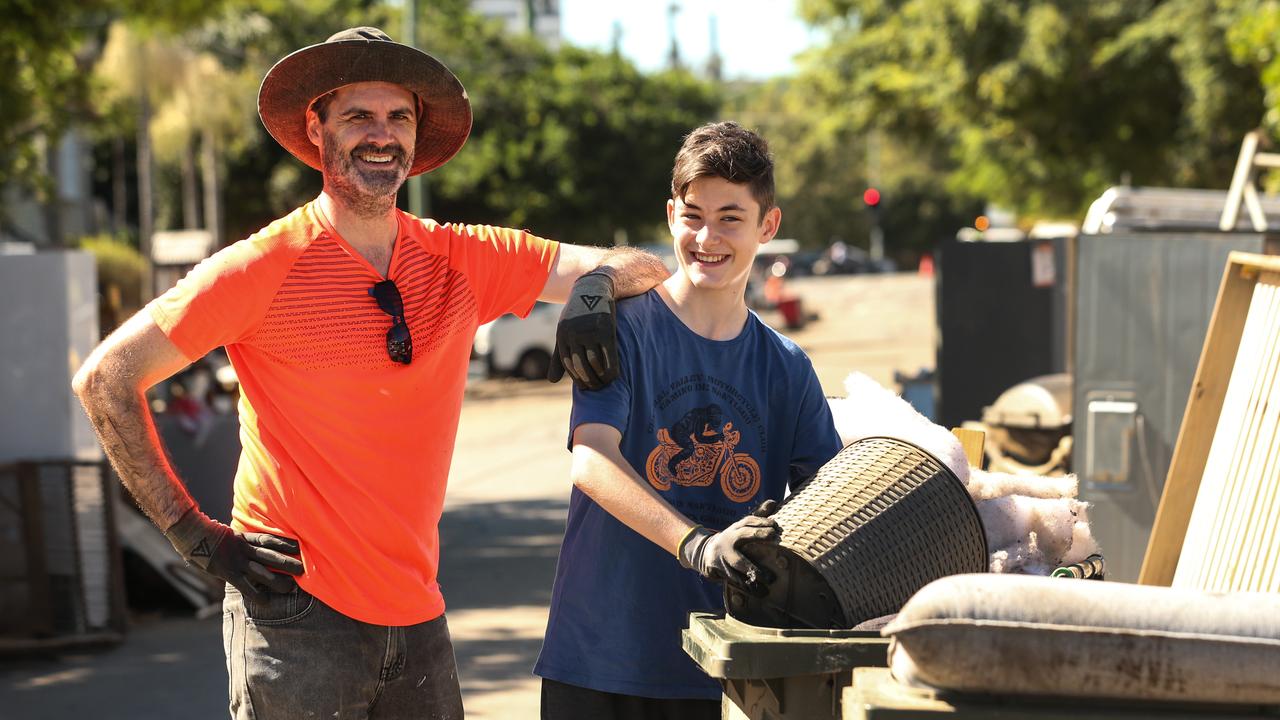 Steven Hender alongside 13-year-old son Jared help with the clean up at Auchenflower. Picture: Zak Simmonds