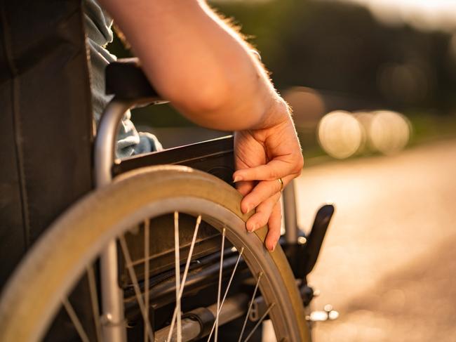 Close up women hand holding wheel on a wheelchair during sunset