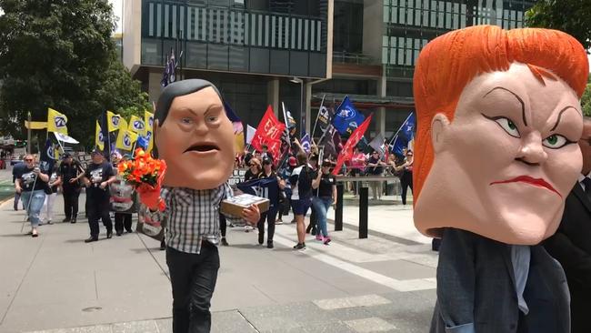 Unions march in Brisbane CBD sporting giant foam masks of Queensland LNP Leader Tim Nicholls and One Nation Senator Pauline Hanson.