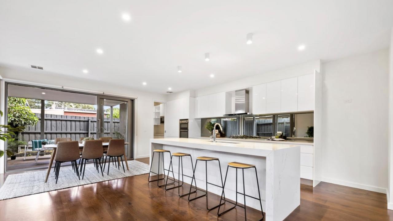 A stone waterfall island, mirrored splashback and premium appliances headline the entertainer’s kitchen.