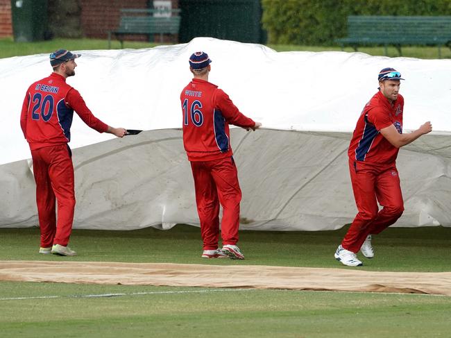 Melbourne players assist in putting covers over the pitch as rain delays play during the Victorian Premier Cricket Kookaburra Men's Premier Firsts Round 3 cricket match between Melbourne and Geelong at Albert Ground in Melbourne, Saturday, October 19, 2019. (AAP Image/Sean Garnsworthy) NO ARCHIVING, EDITORIAL USE ONLY, IMAGES TO BE USED FOR NEWS REPORTING PURPOSES ONLY, NO COMMERCIAL USE WHATSOEVER, NO USE IN BOOKS WITHOUT PRIOR WRITTEN CONSENT FROM AAP