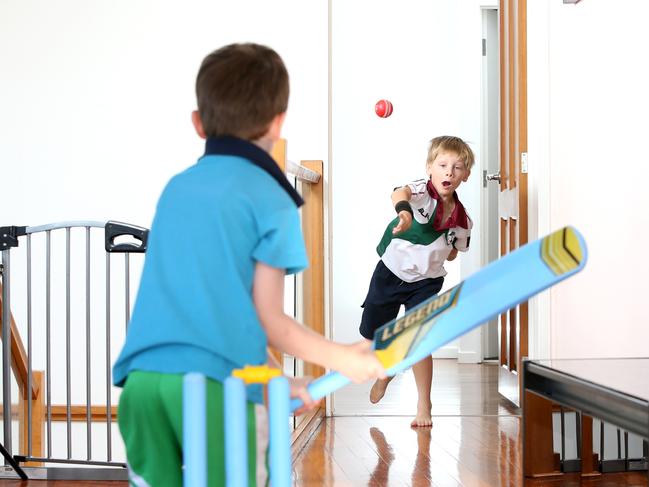 Kai Ryan, 7, bowls to brother Rio, 5, as they play ‘indoor cricket’. Picture: Steve Pohlner/AAP